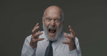 Angry aggressive corporate businessman shouting at camera, he is stressed and frustratedの写真素材