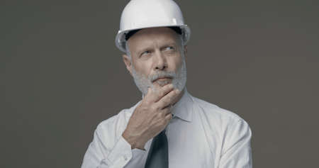 Confident senior businessman and engineer thinking with hand on chin