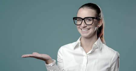 Confident young businesswoman showing something to the camera and smilingの写真素材