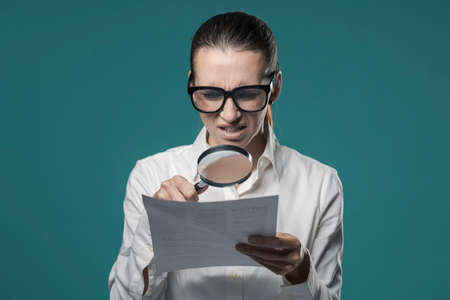 Disappointed businesswoman checking a contract, she using a magnifier and readingの写真素材