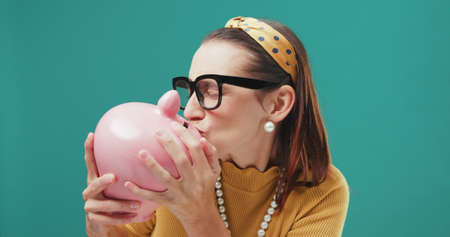Happy woman kissing a money box, savings and successful investments conceptの写真素材