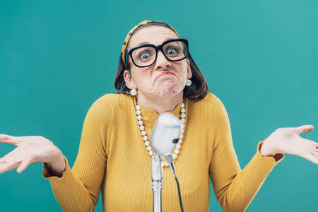 Clueless frustrated woman looking at camera and shrugging in front of a microphone
