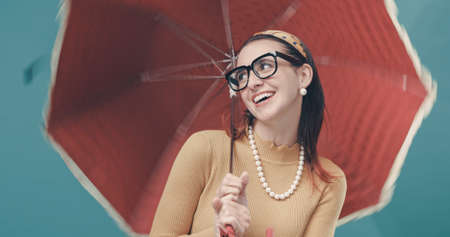 Smiling woman holding a red umbrella, she is happy and carefree