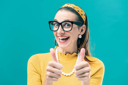Cheerful vintage style woman giving a thumbs up and smiling at camera