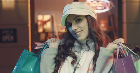 Young woman walking in the city streets and carrying shopping bags, she is happy and smilingの写真素材