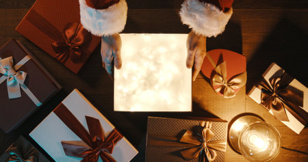 Santa Claus opening a precious Christmas gift on his desktop, there is a sparkling surprise inside