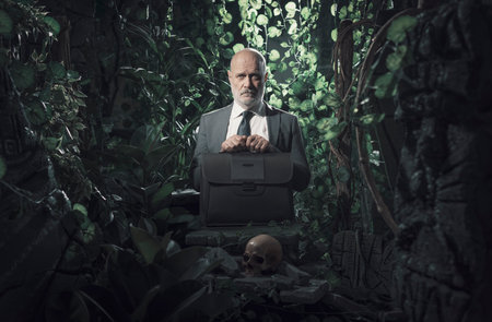 Sad corporate businessman lost in the jungle, he is standing next to ancient ruins and a skullの写真素材