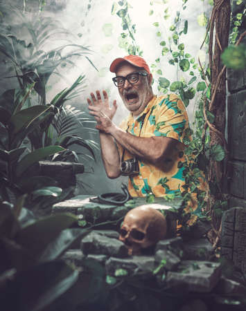 Terrified tourist finding a dangerous snake in the forest, human skull in the foregroundの写真素材