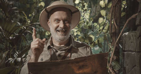 Cheerful adventurer exploring the jungle, he looks at the map and has a great ideaの写真素材