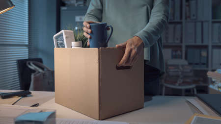 Sad woman packing her belongings in the office after being firedの写真素材