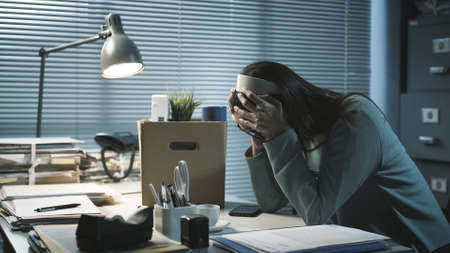 Desperate woman packing her belongings and crying after losing her jobの写真素材
