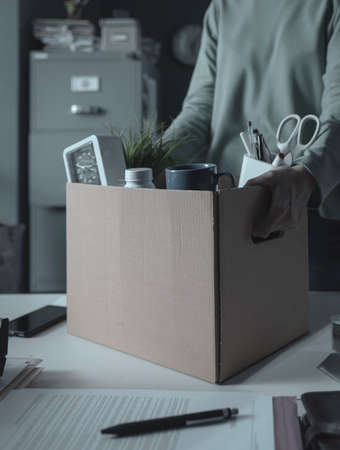 Businesswoman collecting her belongings in a box after being firedの写真素材