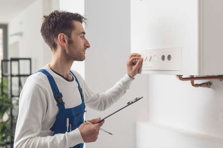 Professional plumber checking a boiler control panel, he is adjusting a knobの写真素材