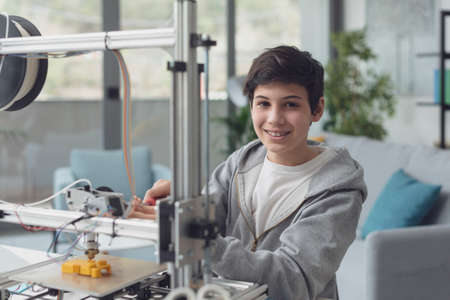 Smart young boy learning how to use a 3D printer at home, science and technology concept