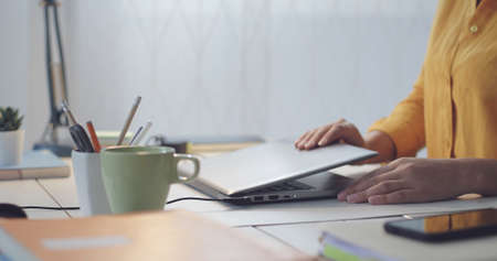 Woman sitting at desk and opening the laptop lid