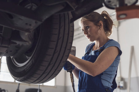 Professional female mechanic doing a wheel replacement in the auto repair shopの写真素材
