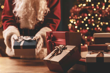 Santa Claus putting Christmas gifts on a table, holiday and celebration conceptの写真素材