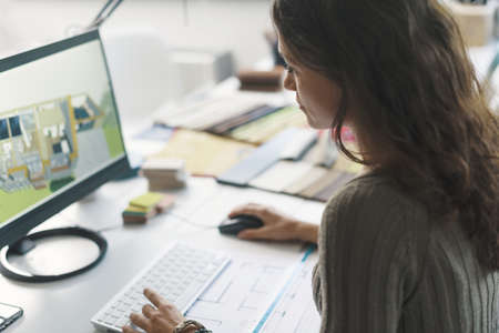 Woman sitting at desk and working on a interior design projectの写真素材