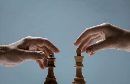 Chess players challenging each other, they are holding the pieces and facing each otherの写真素材