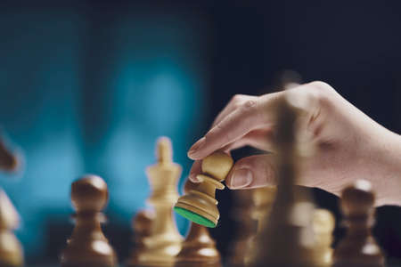 Professional player moving a pawn on the chessboard, strategy games concept