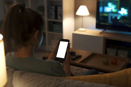 Teenager relaxing on the couch at home and connecting online using her smartphone, screen mock-up