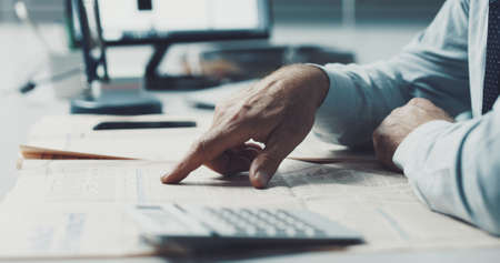 Businessman checking stock market news on a financial newspaperの写真素材