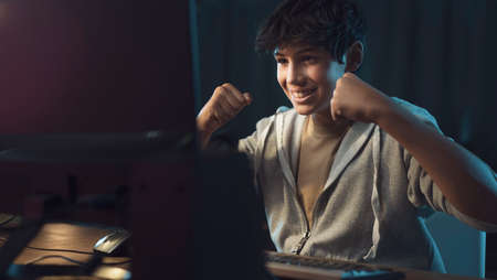 Happy young teenager playing with his computer and winning at video games