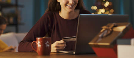Happy young woman doing online shopping at Christmas using a credit card