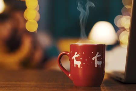 Cute decorated Christmas cup with hot coffee and lights in the backgroundの写真素材