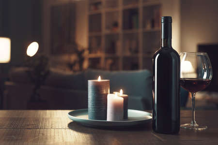 Romantic wine tasting at home with lit candles and room interiorの写真素材