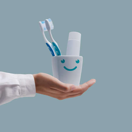 Dentist showing toothbrushes and toothpaste in a cute smiling toothbrush holder, dental hygiene...