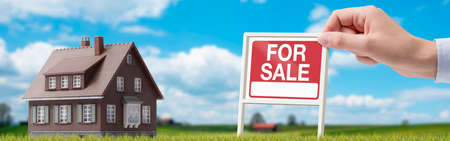 Real estate agent holding a sign and property for saleの写真素材