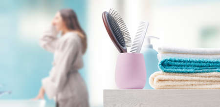 Young woman in the bathroom at home and accessories in the foreground
