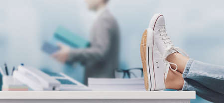 Woman taking a break from her work, she is relaxing with feet up on the deskの写真素材