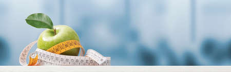 Apple and tape measure on the nutritionist desk, healthy diet and weight loss concept, banner with copy spaceの写真素材
