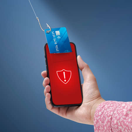 Phishing and cyber security: hacker stealing a user's credit card information on a smartphoneの写真素材