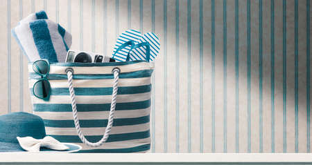 Beach bag with accessories and vintage wallpaper in the background, summer vacations at the beach conceptの写真素材