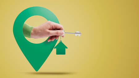 Hand holding house keys and location pin, real estate conceptの写真素材