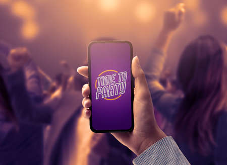 People partying together at the nightclub and woman holding a smartphone in the foreground, POV shot