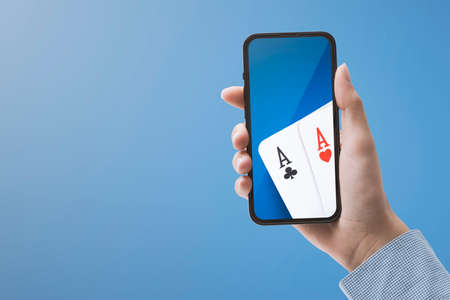 Woman playing poker online on her smartphone, casino and online gambling games conceptの写真素材