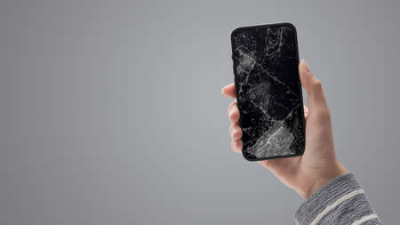 Woman holding a smartphone with cracked screen, smartphone repair service concept