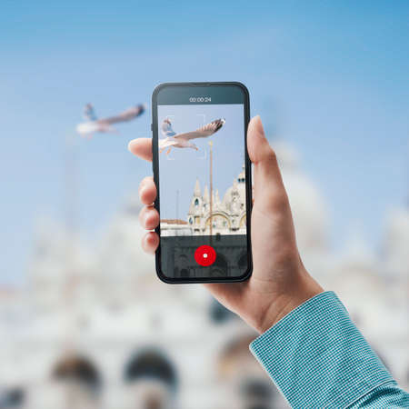 Tourist exploring cities and shooting a video of a seagull flying next to a historical building, POV...
