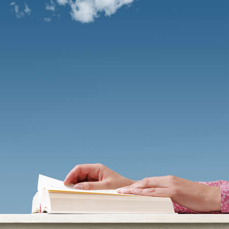 Woman reading a book and blue sky: education, knowledge and freedom concept, blank copy space