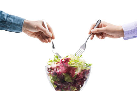 Man and woman eating a fresh salad together, healthy lifestyle concept Isolated on white backgroundの写真素材