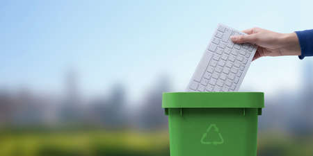 Woman putting a computer keyboard in the e-waste trash bin, recycling conceptの写真素材