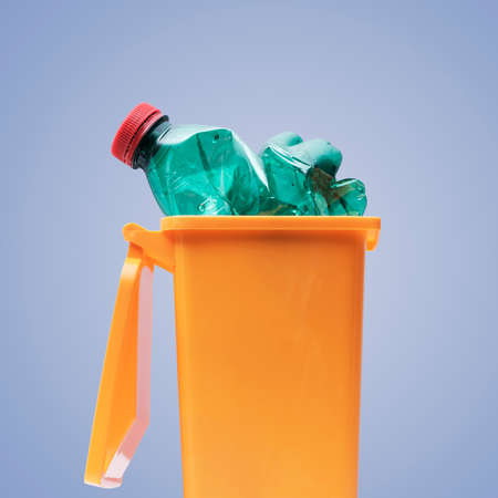 Plastic bottle in a small garbage can, recycling and separate waste collection conceptの写真素材