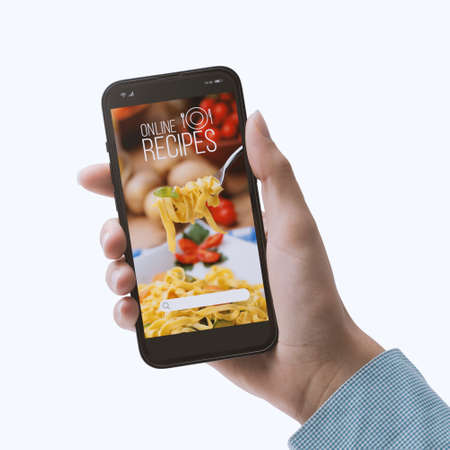 Woman searching for healthy recipes on a cooking app using her smartphone, POV shot On white backgroundの写真素材