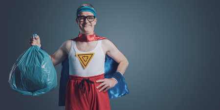 Smiling funny eco-friendly superhero holding a trash bag: recycling, ecology and separate waste collection conceptの写真素材