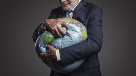 Greedy corporate businessman crushing a globe: earth exploitation and power conceptの写真素材