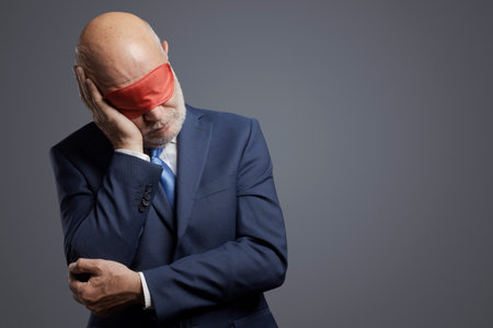 Sleepy careless businessman sleeping and wearing a sleep mask over his eyesの写真素材